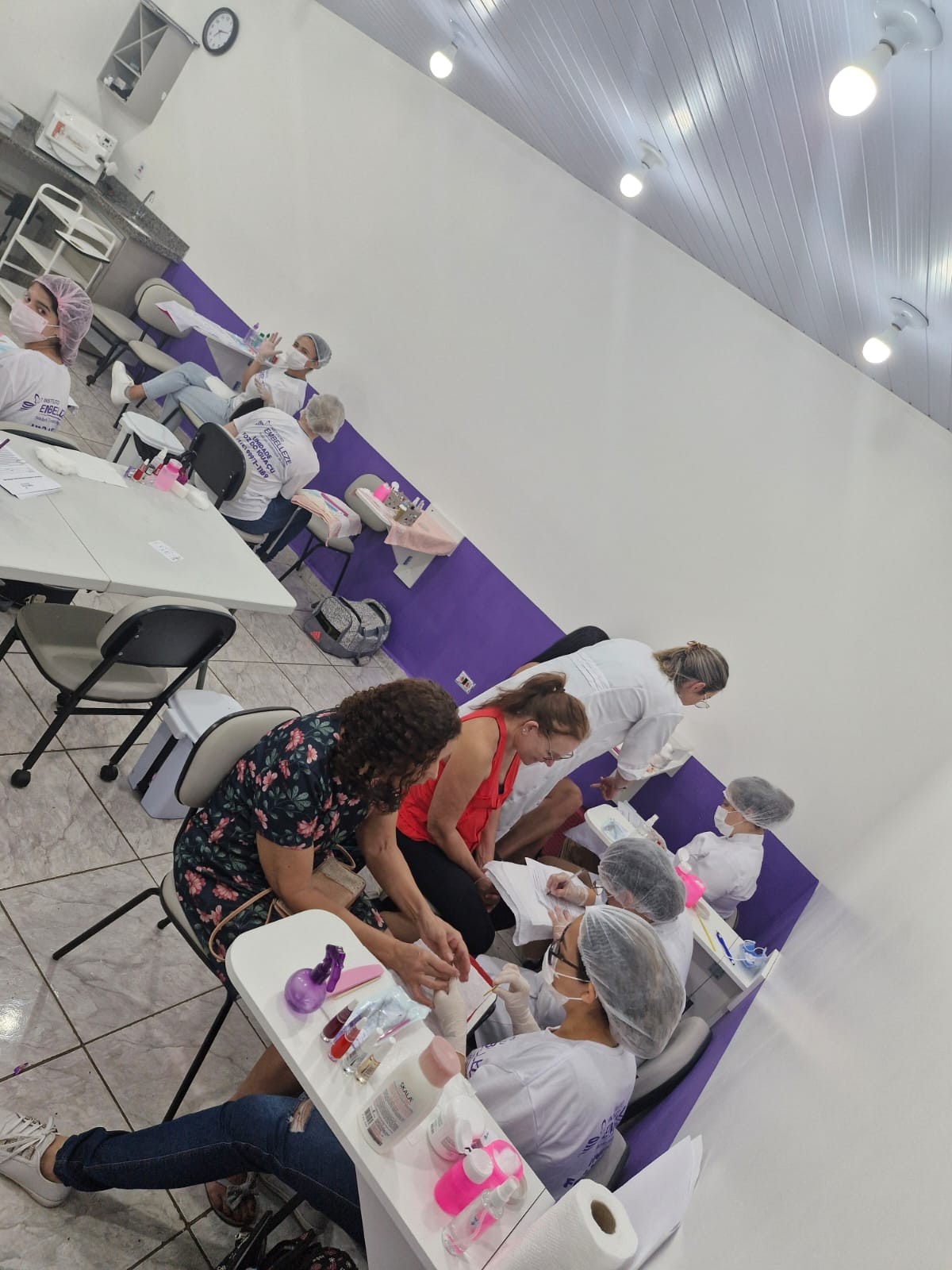 Alunas praticando manicure com acompanhamento das professoras
